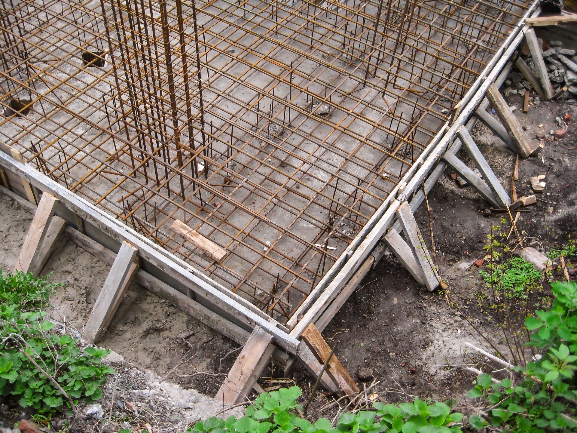 Reinforced steel bars and formwork installed for a concrete foundation slab at a construction site.