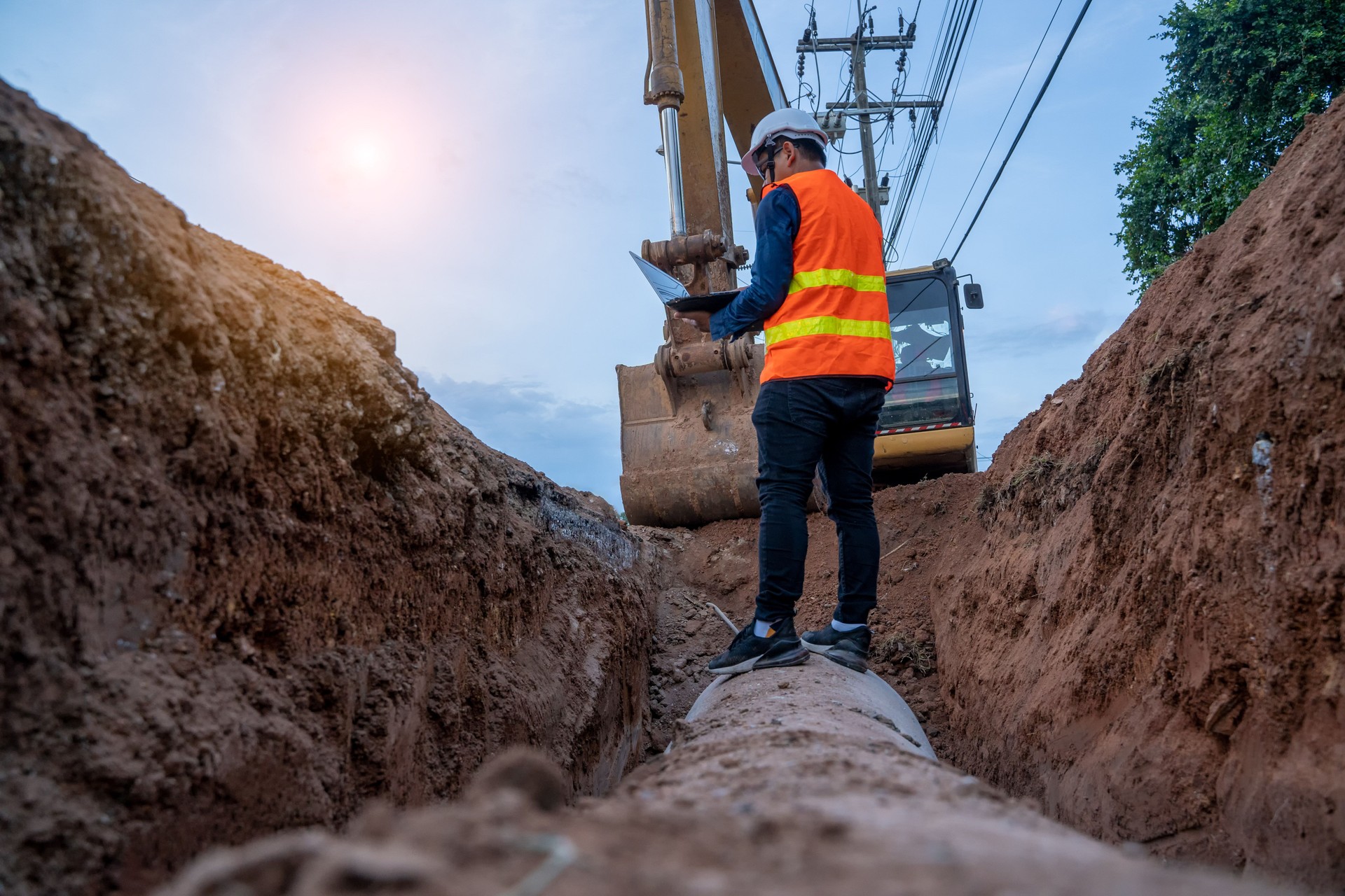 Engineer wear safety uniform examining excavation concrete Drainage Pipe and manhole water system underground.